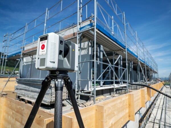 Scanner laser statique sur trépied devant un bâtiment entouré d'échafaudages