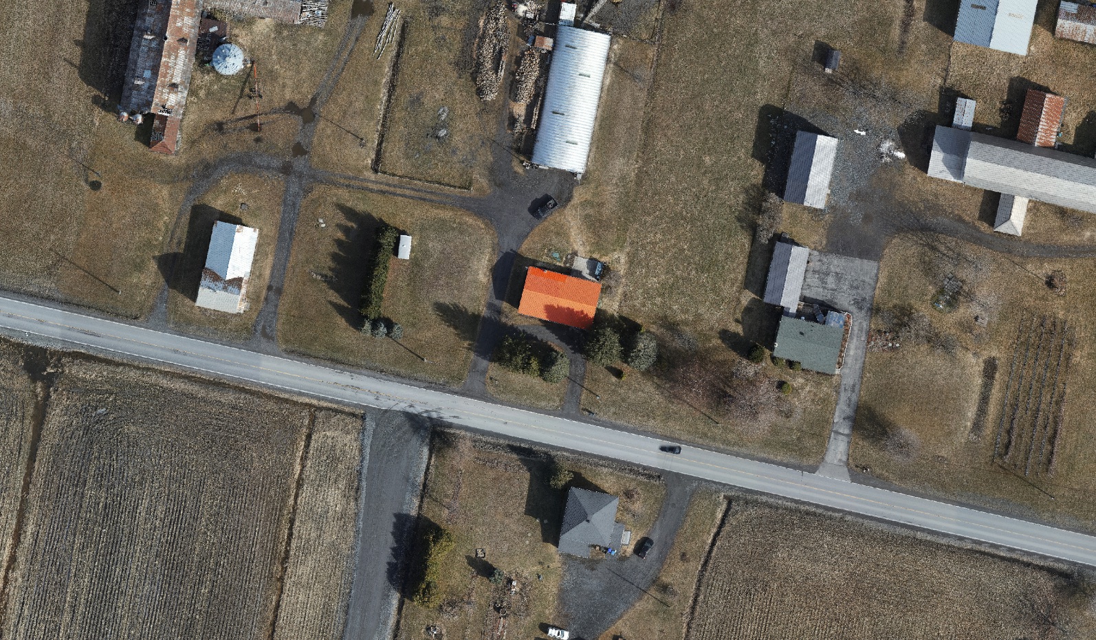 Orthophotographie d'un secteur rural dont un bâtiment ressort en orange, isolé par une analyse spatiale