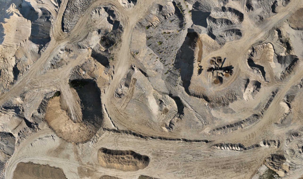Orthophotographie verticale d'une carrière en exploitation : fronts, pistes et installations de concassage